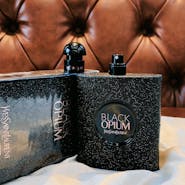 Black Opium perfume bottle on a wooden surface with a leather background