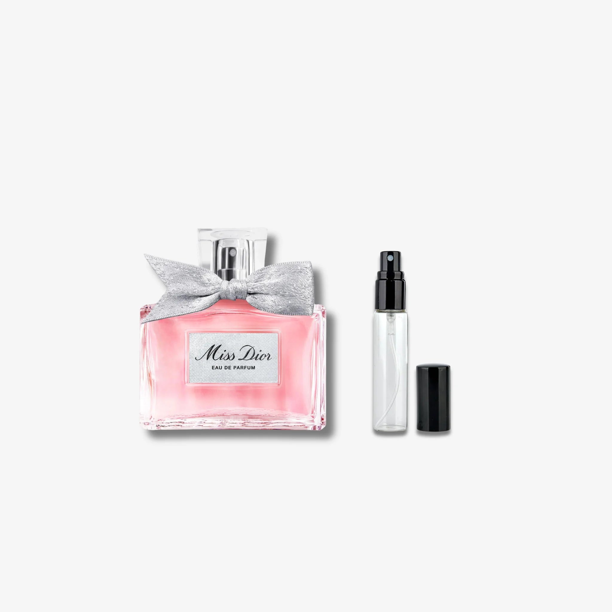 Miss Dior perfume bottle with a silver bow and a smaller travel-sized bottle on a white background